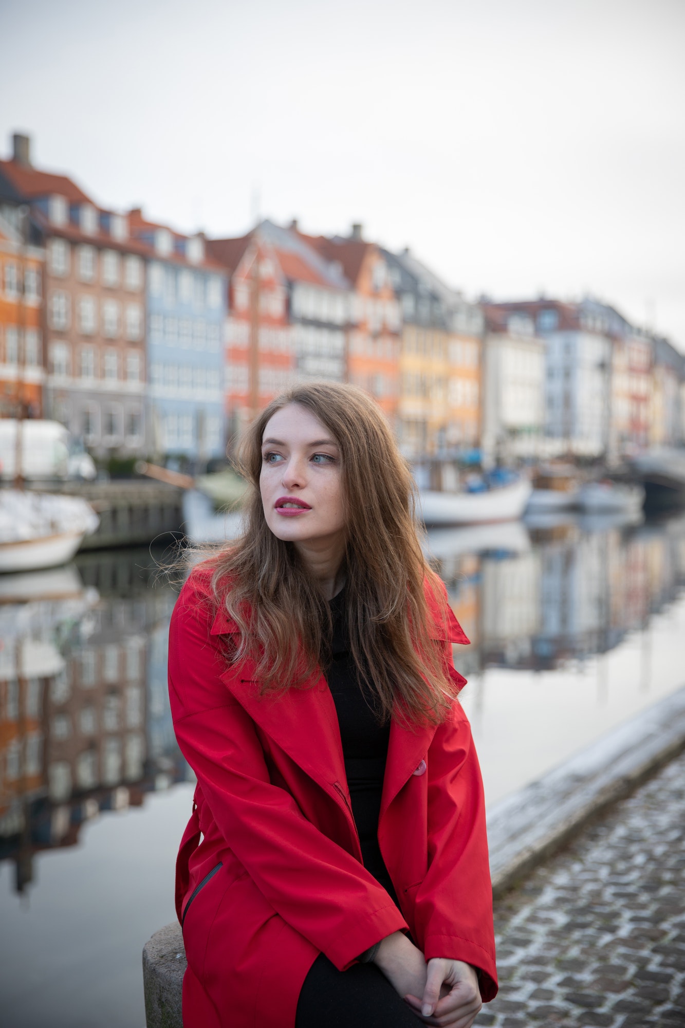 Attractive girl sitting, she is a tourist and is visiting Nyhavn in Copenhagen, Denmark.